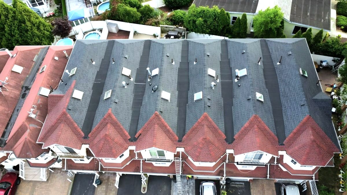 Aerial of rowhouse roofs with dark shingles and red dormer sections